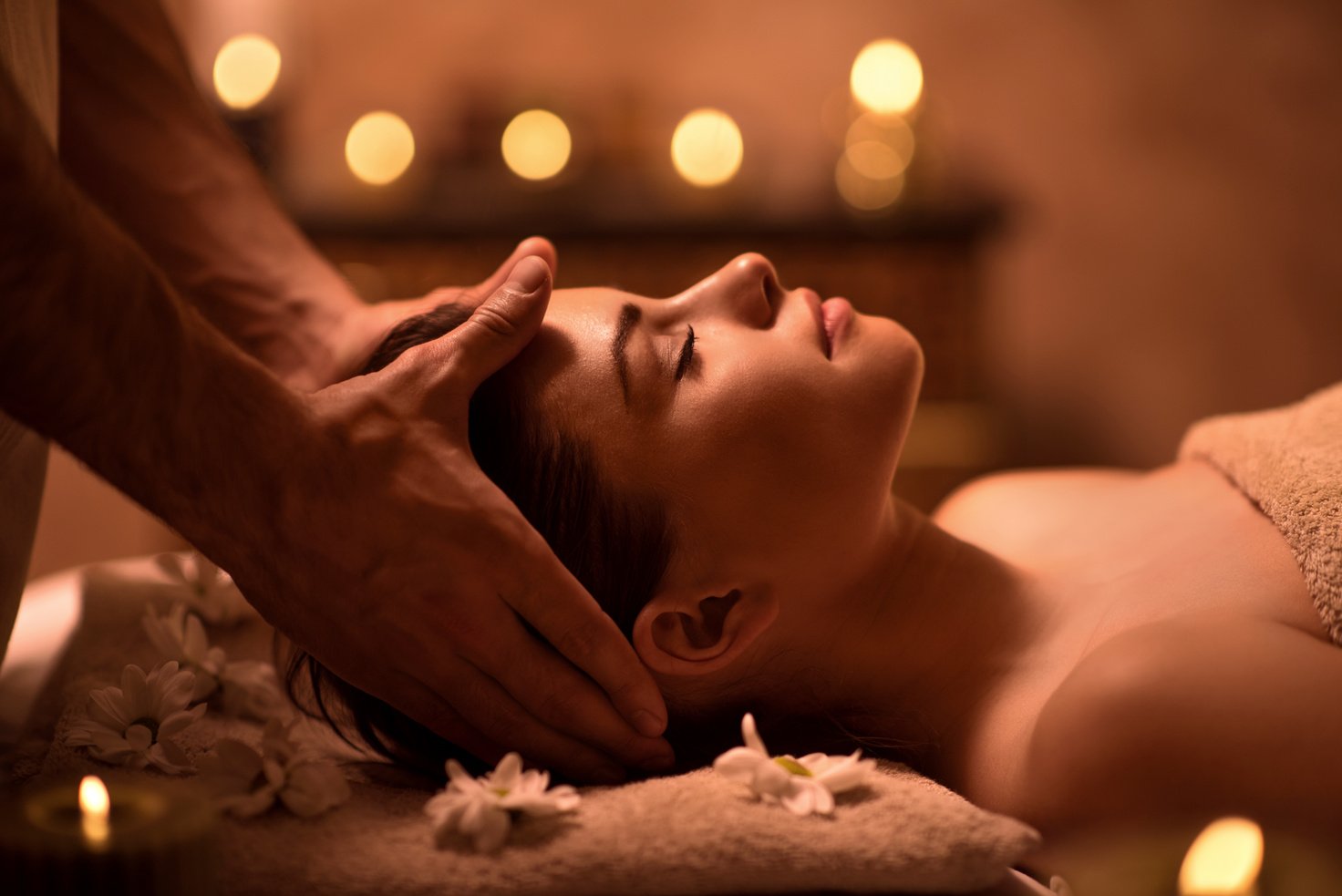 Relaxed woman receiving head massage at spa.